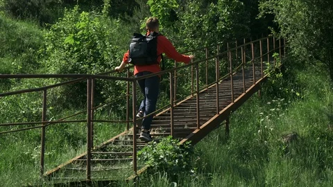 A young guy in a red jacket and a black backpack travels to abandoned places. Video stock 129274460