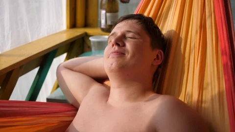 Young guy relaxing and sunbathing on the hammock Vidéo 114076496