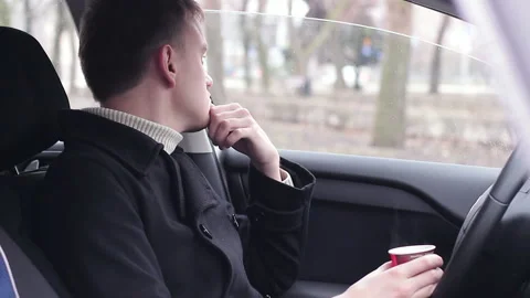 Young guy relaxing in the car and drinks coffee Stock Footage 104762995