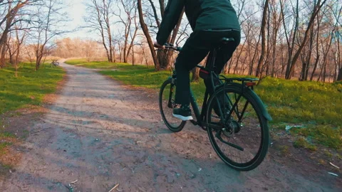 Young Guy Rides a Bicycle Along a Path in a Green Forest, Rear View in Slow Mo Stock Footage 181963202