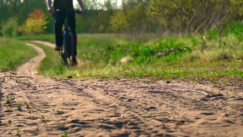 Young Guy Rides a Bicycle Along a Dusty Path in the Forest at Sunset Stock Footage 194008170
