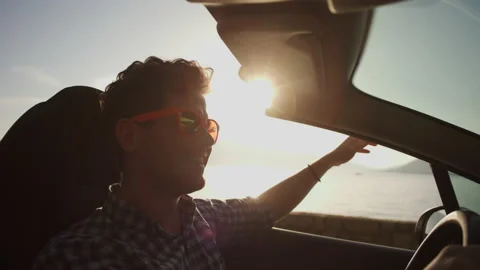 Young guy rides in a convertible along the ocean on a journey. Concept of Stock Footage 229520517