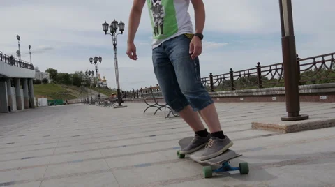 A young guy riding a longboard along the waterfront and makes tricks Video stock 64811573