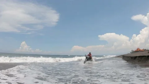 Young guy riding on the ocean shore by the custom motorbike on a sunny day, the  Stock Footage 130838865