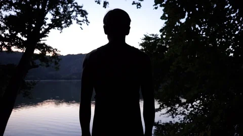 Young guy by the river, silhouette after sunset Stock Footage 114631337