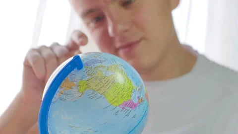 A young guy rotates the globe. Tourist choosing where to travel on a globe Stock Footage 121509963
