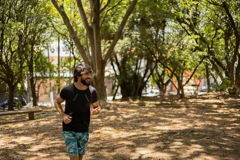 Young guy running and jogging at a park outdoors. Athlete male person during  Stock Photos