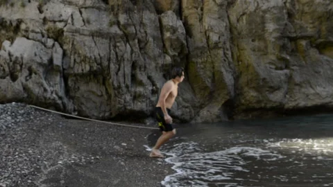 Young guy runs up and jumps into the sea Video stock 103807435