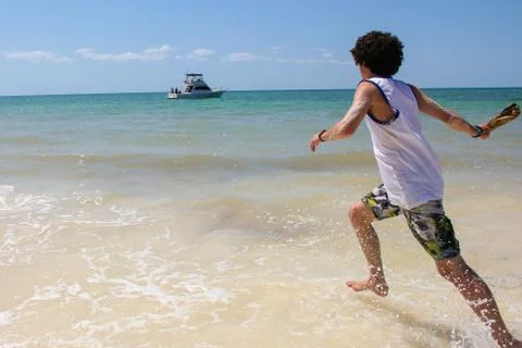 A young guy runs into the sea. Stock Photos