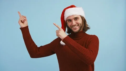 Young guy in Santa hat is pointing up at something, winking and smiling while Stock Footage 145077480