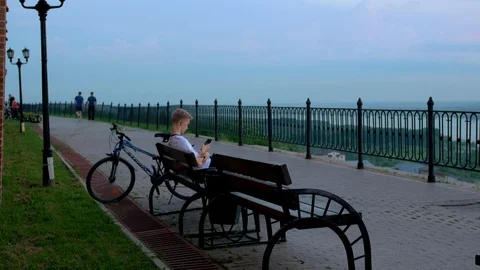 A young guy sat down on a bench sends a message on a smartphone. Stock Footage 104059002