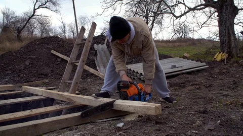 Young guy saws a rafter with a chainsaw Stock Footage 120253357