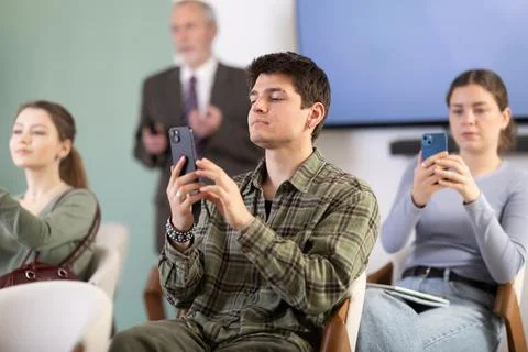 Young guy scanning QR-code with mobile devices during presentation Stock-Fotos