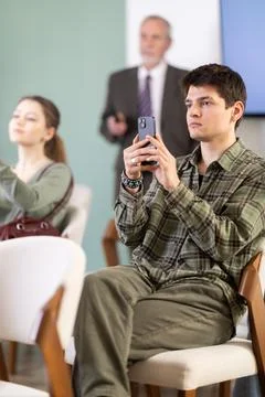 Young guy scanning QR-code with mobile devices during presentation Stock Photos