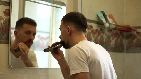 A young guy shaves in front of a mirror Stock Footage 309794874