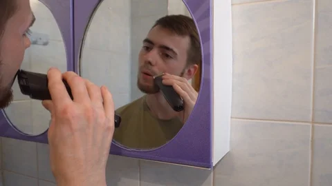 Young guy shaves his beard with a trimmer Stock Footage 114751486