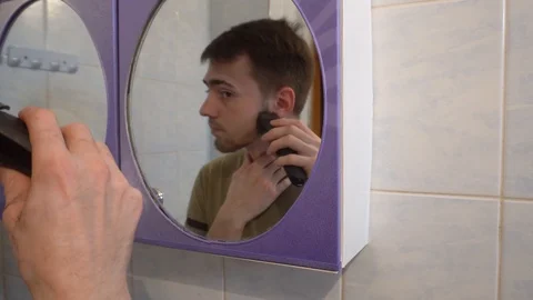 Young guy shaves his beard with a trimmer 库存影片 114751616