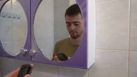 Young guy shaves his beard with a trimmer Stock Footage 114751779