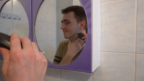 Young guy shaves his beard with a trimmer Stock Footage 114751793