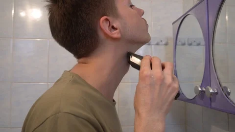 Young guy shaves his beard with a trimmer Stock Footage 114752011