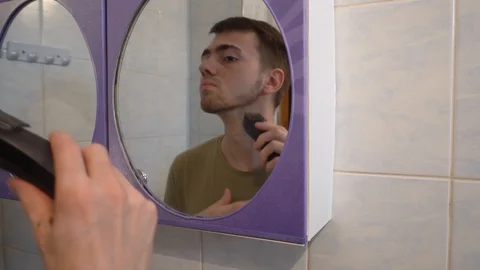 Young guy shaves his beard with a trimmer Stock Footage 114752191