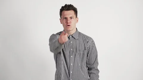 Young guy in shirt on white background expresses his displeasure directly camera Stock Footage 121006536