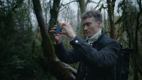 Young guy is shooting video in forest with phone, nature photography on phone Stock Footage 147922482