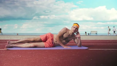 Young guy in shorts without a T-shirt does the exercise of raising his legs. Stock Footage 199252897