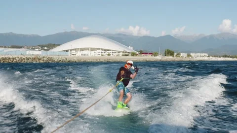 Young guy is showing the goat gesture and sticking his tongue while wakeboarding Stock Footage 201345220