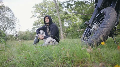 A young guy sits and rests in the woods after riding Stock Footage 117665316