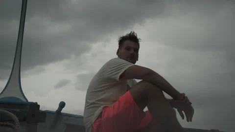 A young guy sits on the bow of the ship Stock Footage 146887306