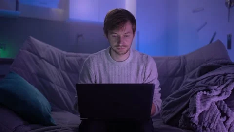 A young guy sits on the couch at home and communicates on social networks Stock Footage 152796992