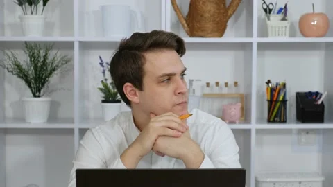 A young guy sits in his office at his laptop and thinks about what to do Stock Footage 170846539