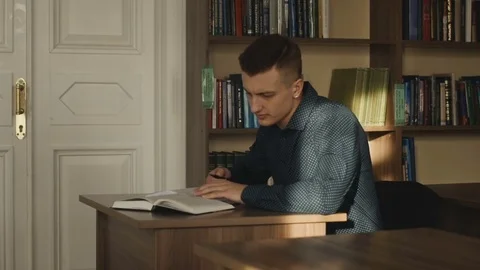 A young guy sits in a library and writes notes Stock Footage 85248055