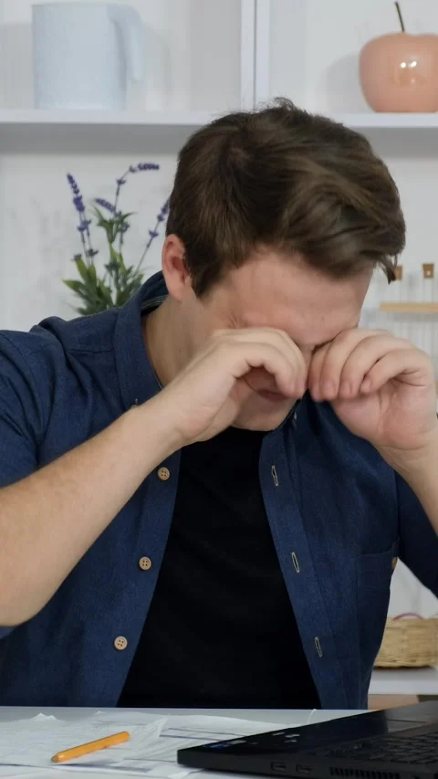 A young guy sits in the office and works on his laptop. Yawning and falling.. Video stock 306137863