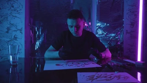 A young guy sits at a table and holds a phone in his hands Vidéo 123576070