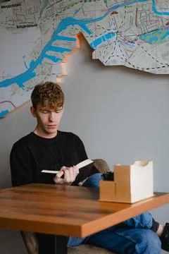 A young guy sits at a table with a book in his hands Stock Photos