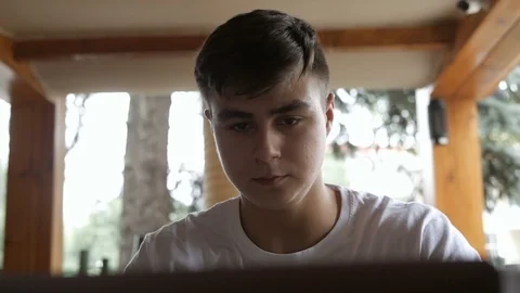 A young guy sitting in a cafe or restaurant using a laptop. Freelancer works Stock Footage 113628983
