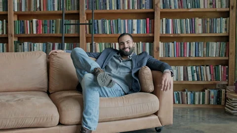 Young Guy Sitting On The Couch In The Library. Stock Footage 140221692