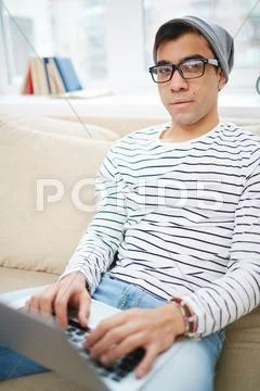Young guy sitting on sofa with laptop Stock Photos