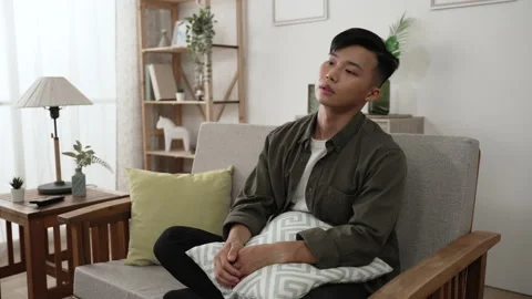Young guy sitting on the sofa with a pillow Stock Footage 160346417