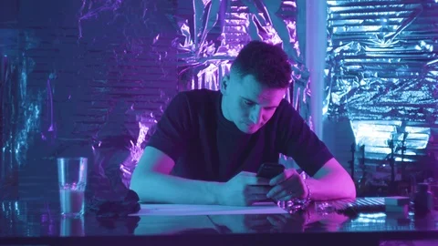 A young guy is sitting at a table and holding a phone. prints a message Vidéo 123575224