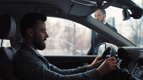 Young guy sitting at wheel in car. Young counselor approaching car, saying Stock Footage 86175101
