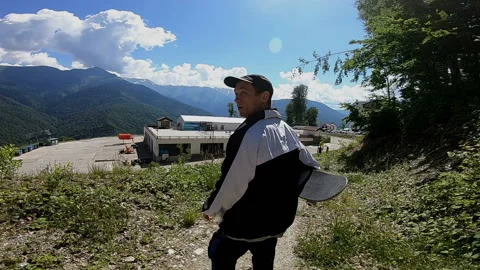 Young guy with a skateboard descends down the path Video stock 102318933