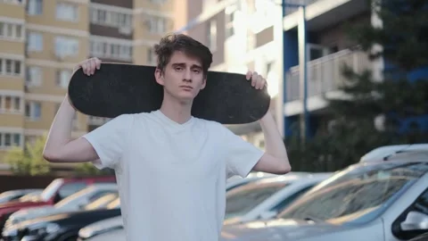 A young guy with a skateboard in his hands near the house Stock Footage 280508229