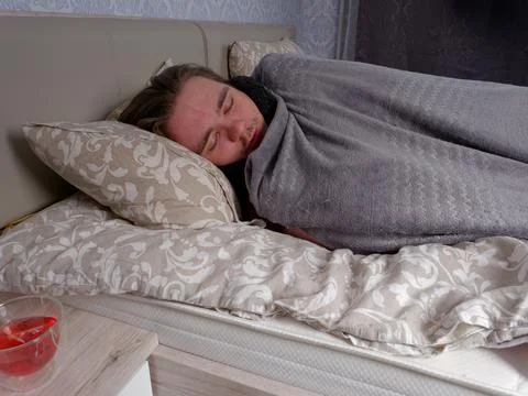 Young guy sleeping in bed in the bedroom after taking cold medicine Stock Photos