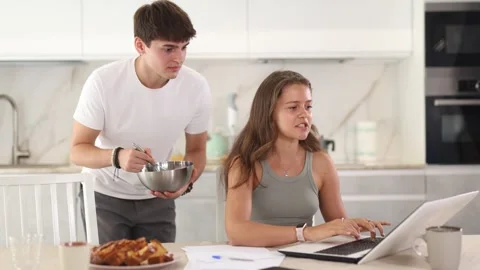 Young guy smiling and chatting with woman working at laptop Stock Footage 335614030