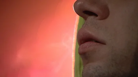 A young guy smokes a cigarette and exhales smoke, smoke fumes swirl and envelop Stock Footage 120577758