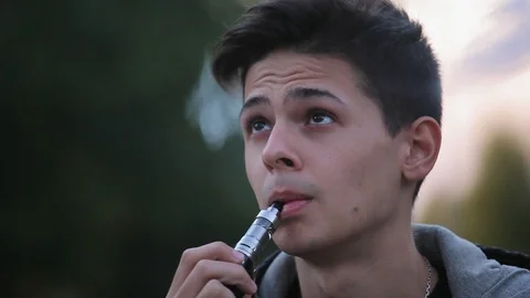 Young guy smokes e-cig outdoors in the evening Video stock 96217126