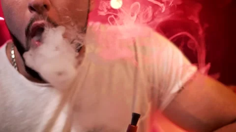A young guy smokes a hookah and lets the rings out of smoke. Close-up Stock Footage 130185832